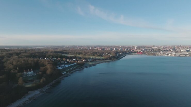 Scatto aereo della costa danese vicino a Marselisborg, con spiagge vuote, acqua calma e alberi spogli: una vista tranquilla del nord Europa in transizione