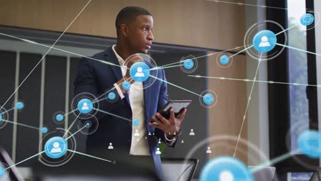 animation of network of connections with icons over african american businessman in office
