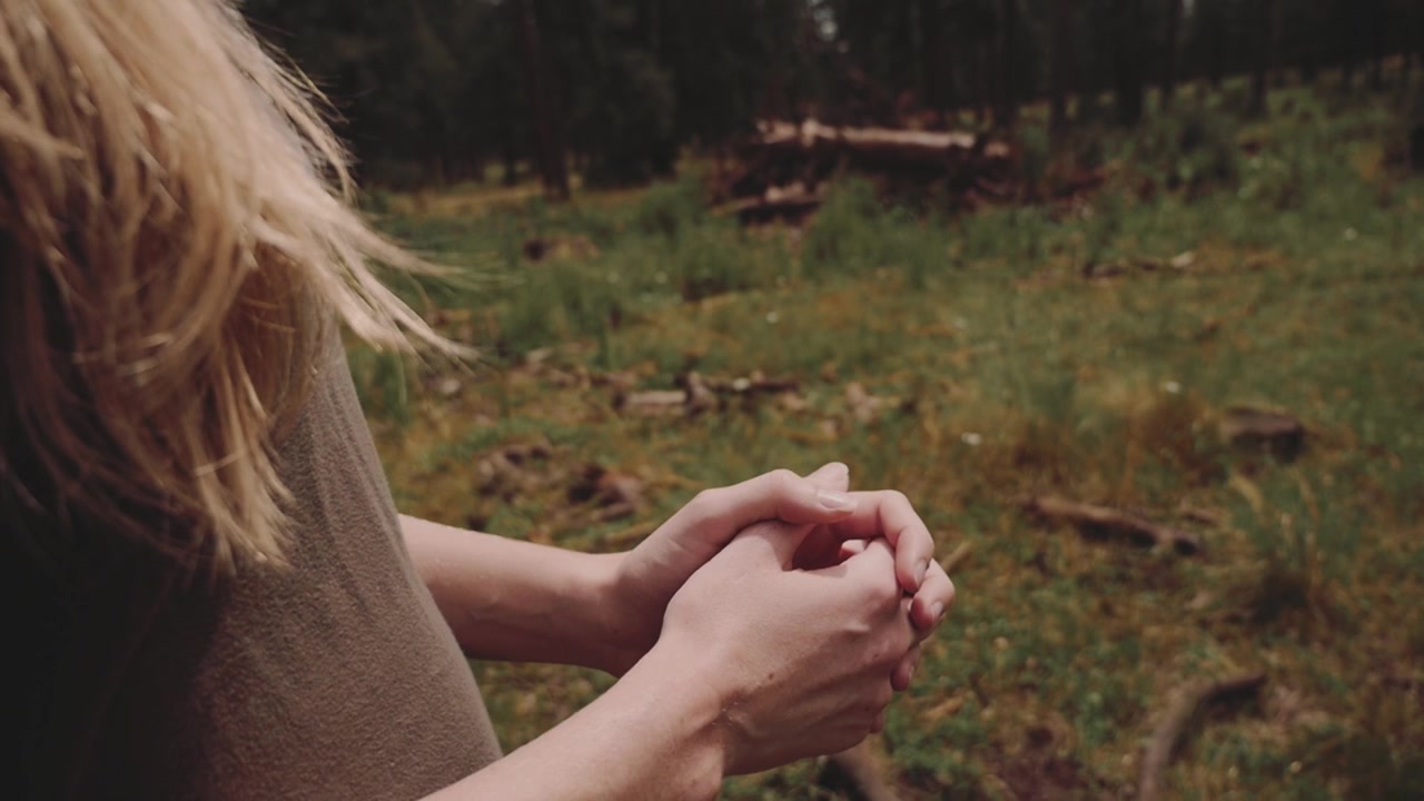 Primo piano delle mani giunte di una donna in una foresta serena