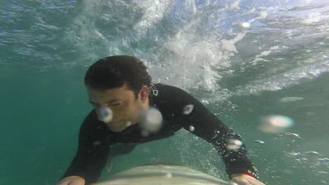 unknown surfer dude paddling on cool surfboard to catch a wave