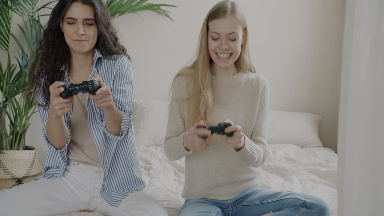 Two Women Playing Video Games in a Bedroom