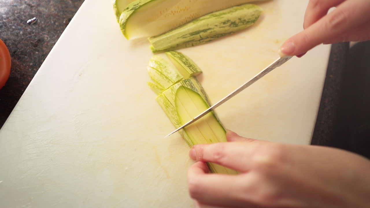 슬로우 모션으로 부엌에서 녹색 호박을 자르는 여성 손