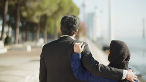 Back-view-of-happy-couple-walking-along-quayside