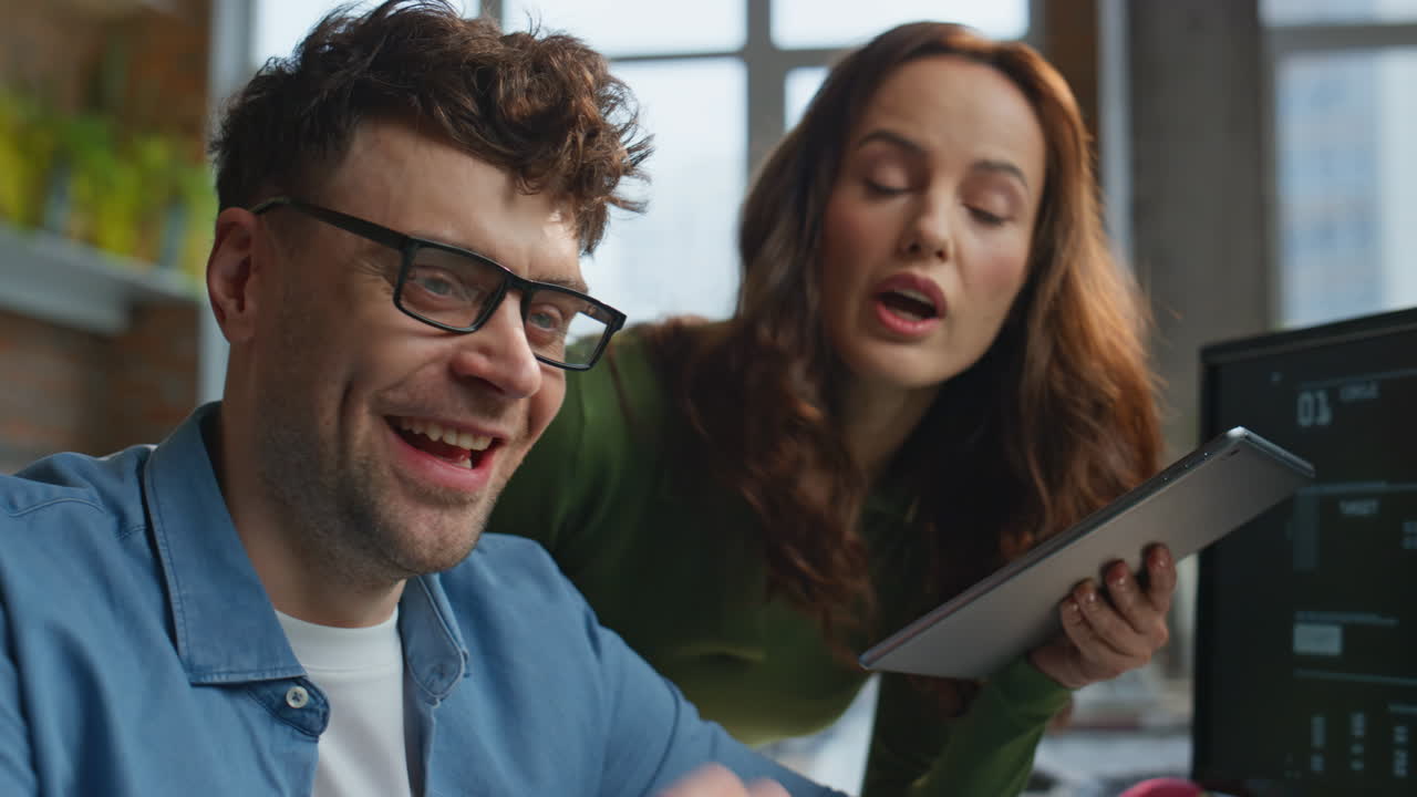 Positive office couple discussing task working together at computer closeup