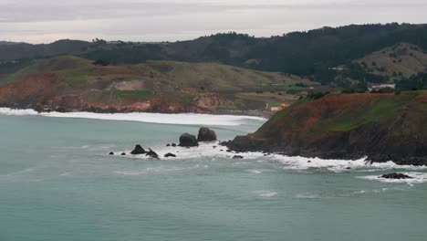 panning to the left drone aerial shot of waves crashing up on rocky peninsulas