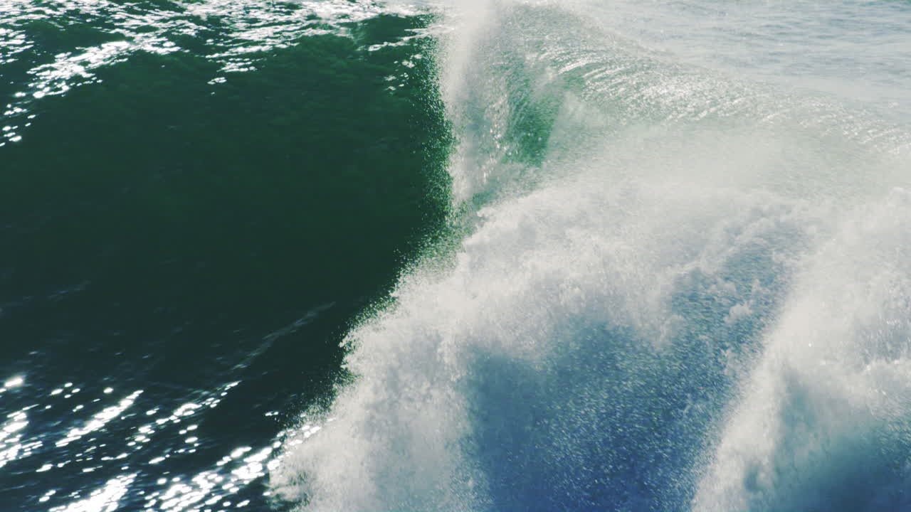 Slow-motion view of a wave barreling over, captured during a sunrise session, highlighting the wave's powerful curl and glassy surface