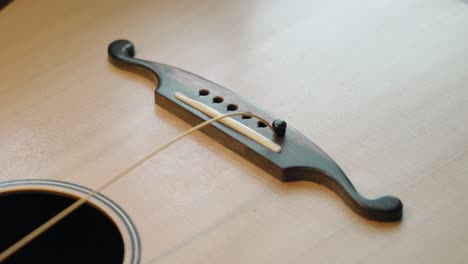 guitarist installing strings onto the bridge of an acoustic guitar