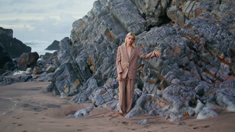 glamour girl modeling beach leaning ocean rocks. sexy blonde in elegant suit