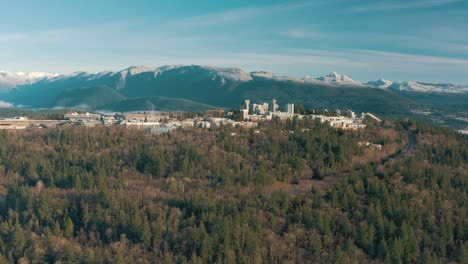 Aerial-view-of-Simon-Fraser-University-on-a-hill-and-mountains-on-background-in-British-Columbia,-Vancouver,-Canada