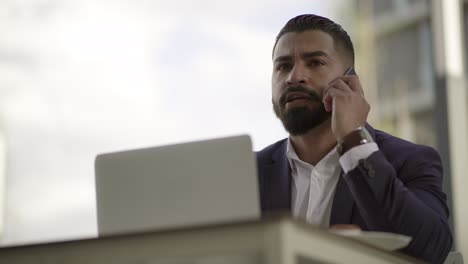 Businessman answering important phone call in outdoor cafe