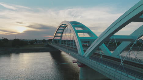 modern arch bridge at sunset over a river