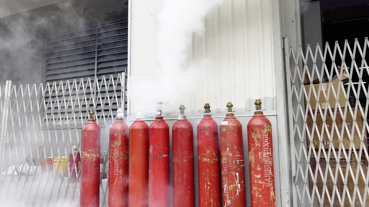 Vapore e aria fuoriescono durante il degassamento di estintori scaduti, processo di rilascio da bombole antincendio dismesse. Ripresa in tilt-up.