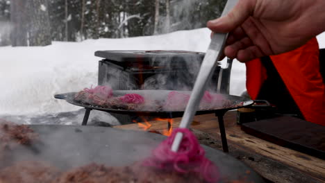 Preparing-steaming-reindeer-burgers-over-flaming-hot-stove-for-Swedish-outside-snowy-barbeque