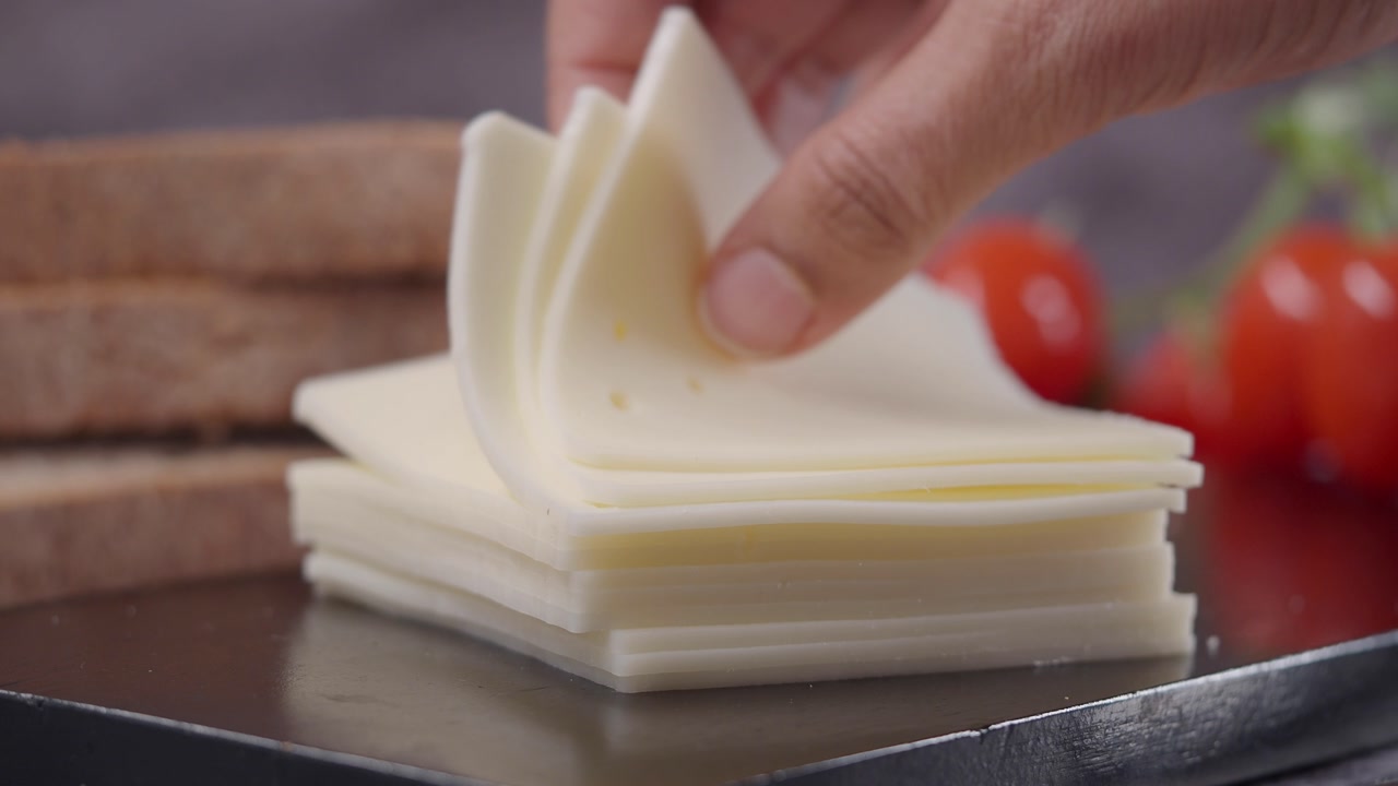Close-up of Hand Lifting Slices of Cheese