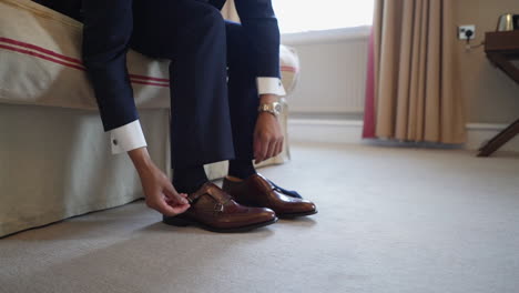 a man sitted on a bed and tieing shoes in marvelous action