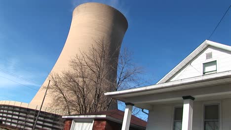 the huge cone of a nuclear power plant looms above a home