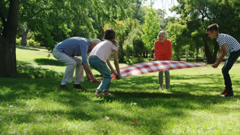 multi-generation family placing blanket in the park