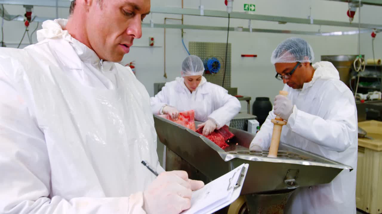 Male butcher writing on clipboard