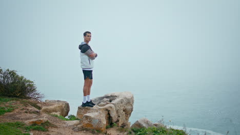 athletic man relaxing sea in fog weather. fit guy resting after running cardio