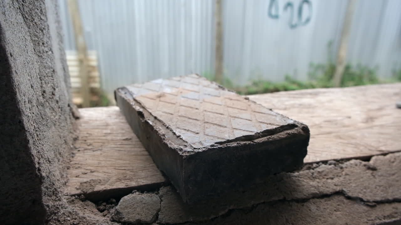 Close-up of a brick made from recycled plastic, placed on a rough surface