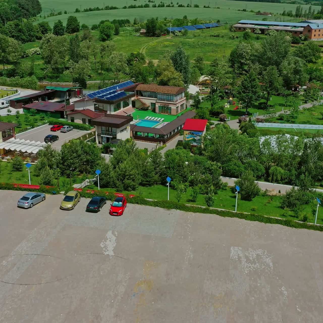 Recreation complex among green nature. Place for car parking near the resting zone. Innovative solar panels on roofs and field in summer. Aerial view.