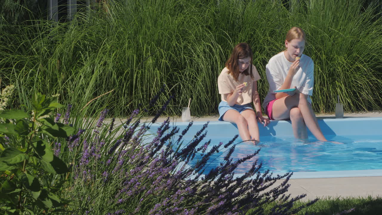 dos chicas relajándose junto a la piscina.