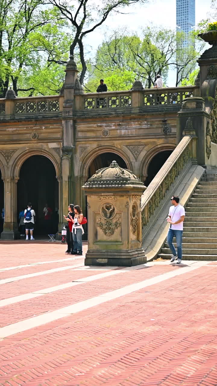 New York, USA, 1 agosto 2025: persone che passeggiano vicino agli archi della Bethesda Terrace a Central Park. Gruppi di visitatori si aggirano davanti al porticato in pietra incorniciato dal verde