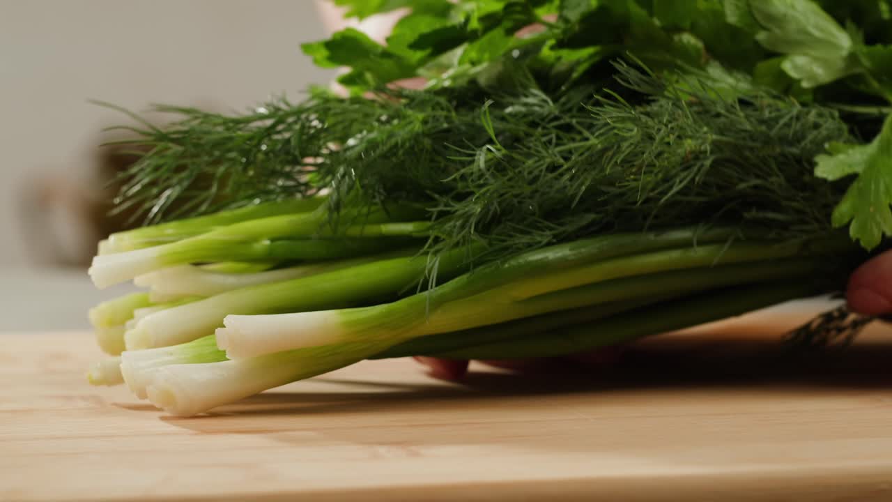 Cutting fresh green onions on a cutting board, close up chef cooking green vegan salad.