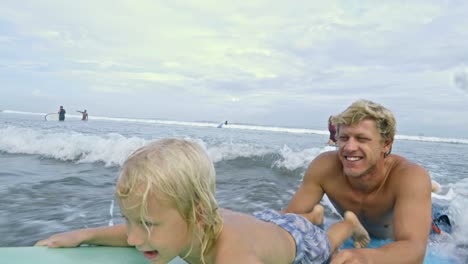father and son swimming on surfboard in ocean