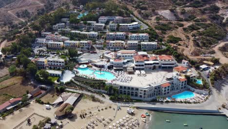 drone flies over the beach in greece on crete in the direction of holiday resort with pools and water park