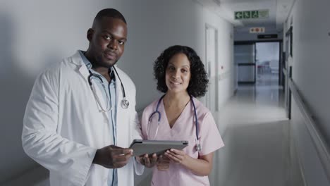 portrait of happy diverse doctors using tablet in hospital in slow motion