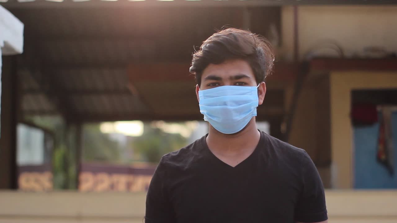 Portrait of a young Indian boy removing protective mask and giving thumbs up sign Close shot. recovered from virus Concept of health and safety life, corona virus, virus protection, pandemic in world