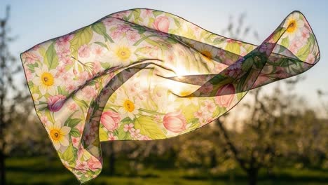 a vibrant floral scarf dancing in the breeze, highlighting nature's beauty under a golden sunlight glow, creating an ethereal and dreamlike ambiance