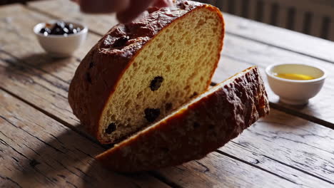 pulling apart freshly baked fruit bread on a rustic table