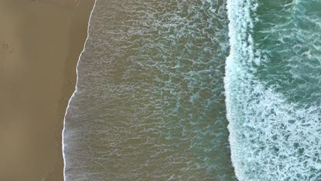 Antena-De-Agua-De-Mar-Espumosa-Rodando-En-La-Costa-Arenosa---Disparo-De-Drones