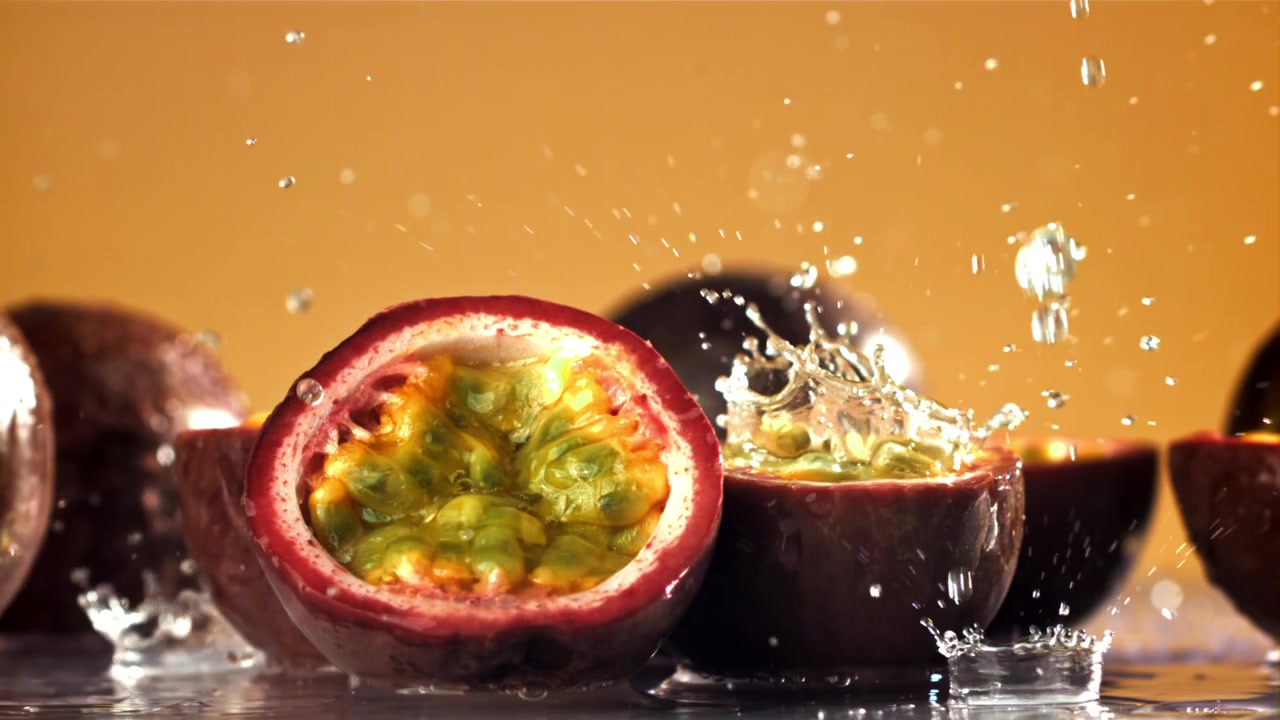 Friske passionsfrugter med vand der sprøjter i slow motion