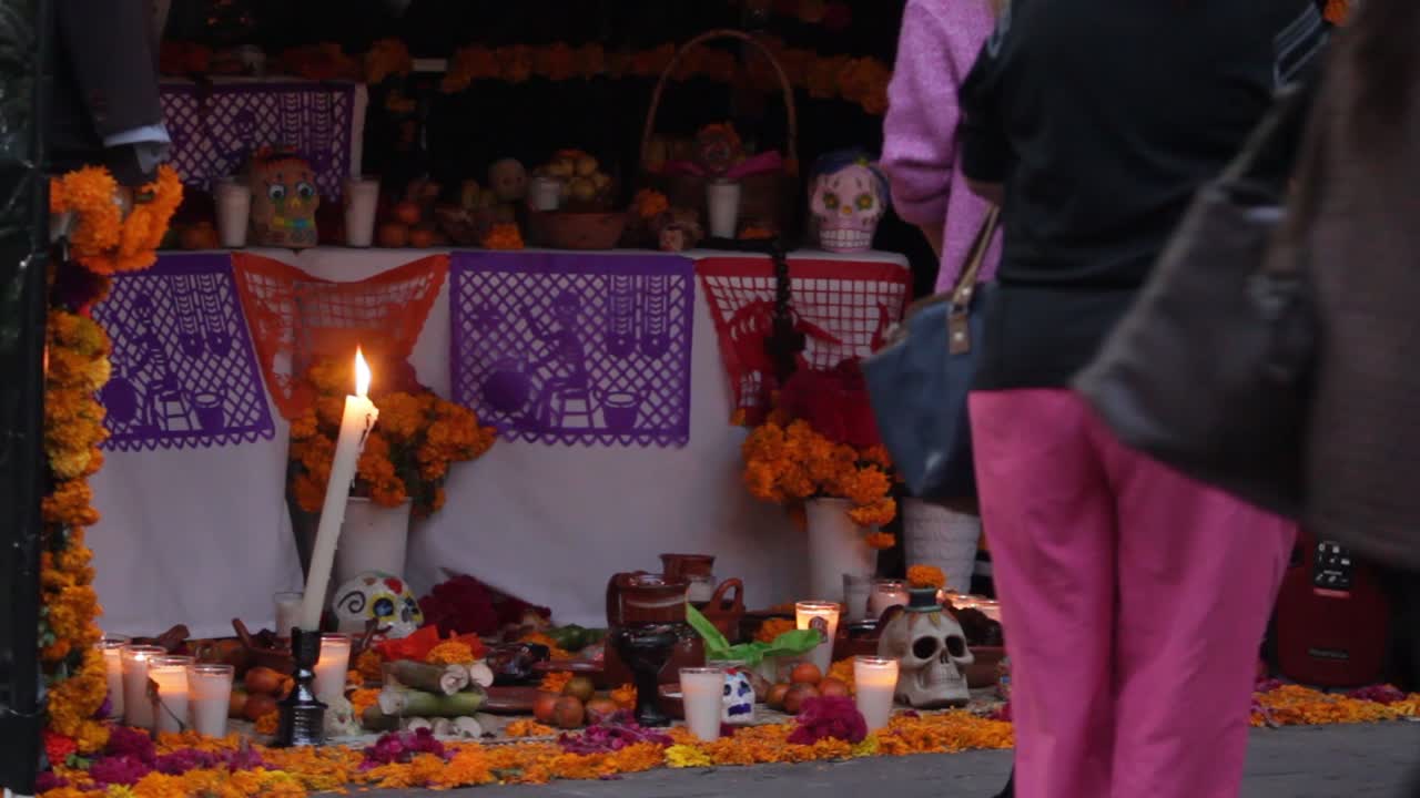 close up of people walking by the altar during day of the dead celebration in mexico, taking pictures