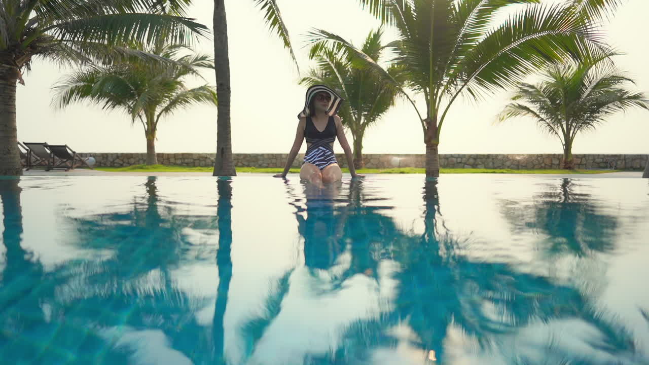 Woman siting in middle of swimming pool, rippling water, soft light, wide shot