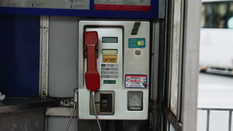 static shot of a telephone in hong kong with people walking in the foreground