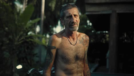 senior man with tattoos in tropical setting