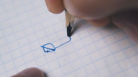 man draws image breaking blue pencil on paper macro