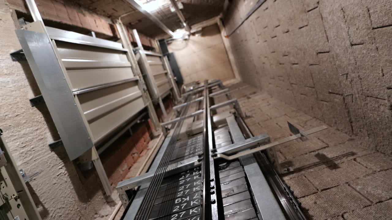 엘리베이터 리프트 캐빈은 여러 층의 느린 동작으로 유압 장치가 있는 조명 엘리베이터 샤프트 내부로 이동합니다.