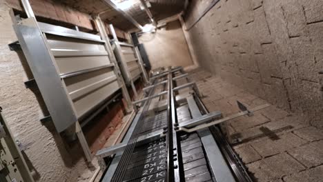 cabina de ascensor se mueve hacia arriba dentro del eje del ascensor iluminado con hidráulica con muchos pisos a cámara lenta