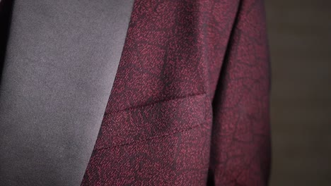 close-up of a hand on a textured maroon suit jacket