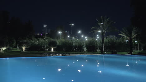 a steadicam shot of an illuminated open pool at night