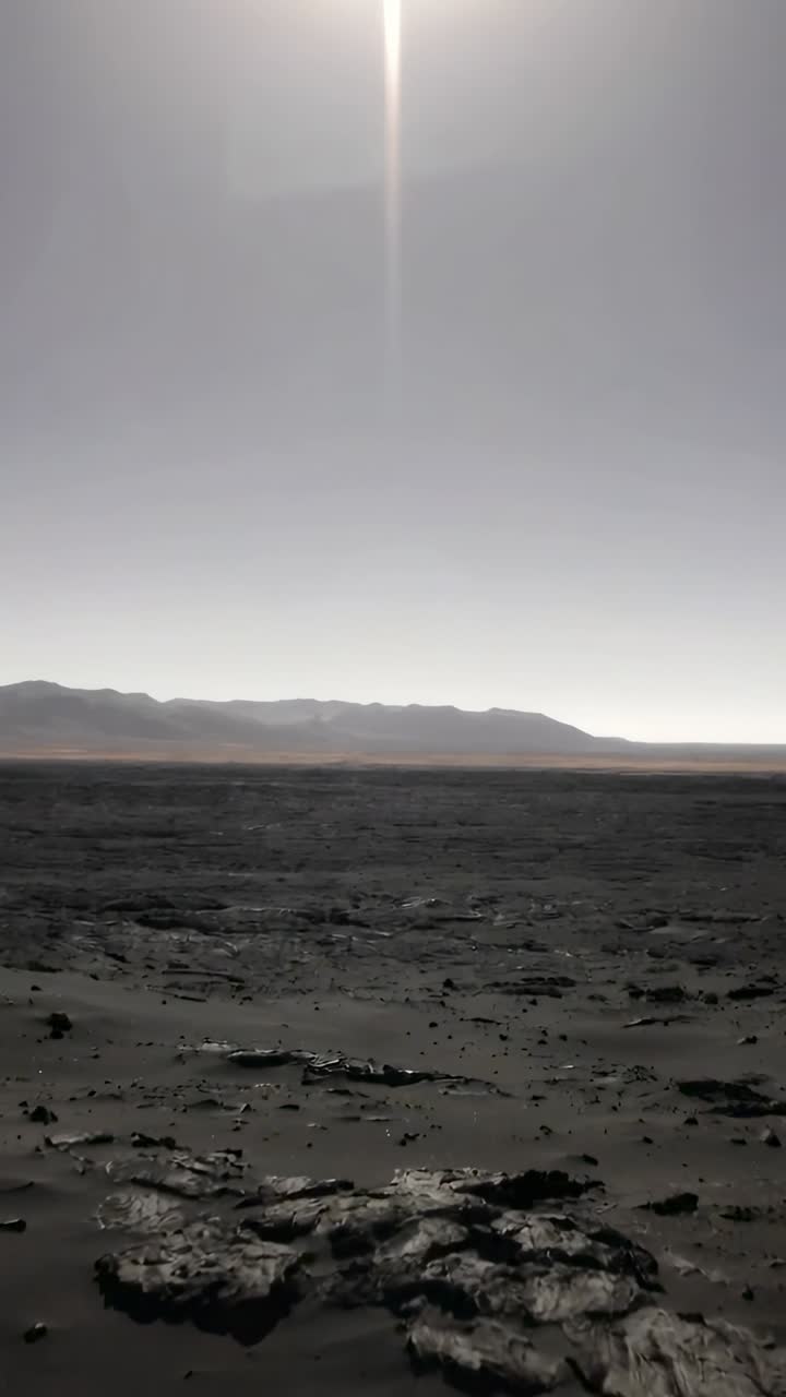 Vertical video: Tilting camera revealing cracked ground on plain, ridge and vertical sun flare