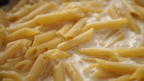 cook adding cream to boiling pasta