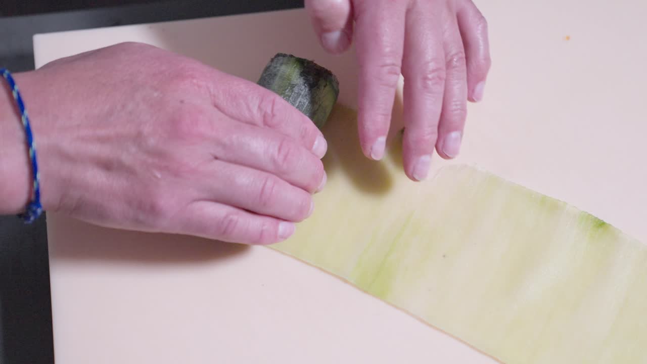 A following shot of a cucumber sushi roll being rolled, showcasing the sushi preparation process. Perfect for highlighting the art of sushi making and fresh ingredients in Japanese cuisine.