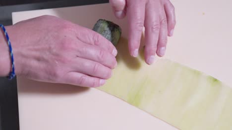 a following shot of a cucumber sushi roll being rolled, showcasing the sushi preparation process. perfect for highlighting the art of sushi making and fresh ingredients in japanese cuisine.