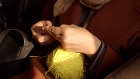 woman knitting with yellow yarn in a car